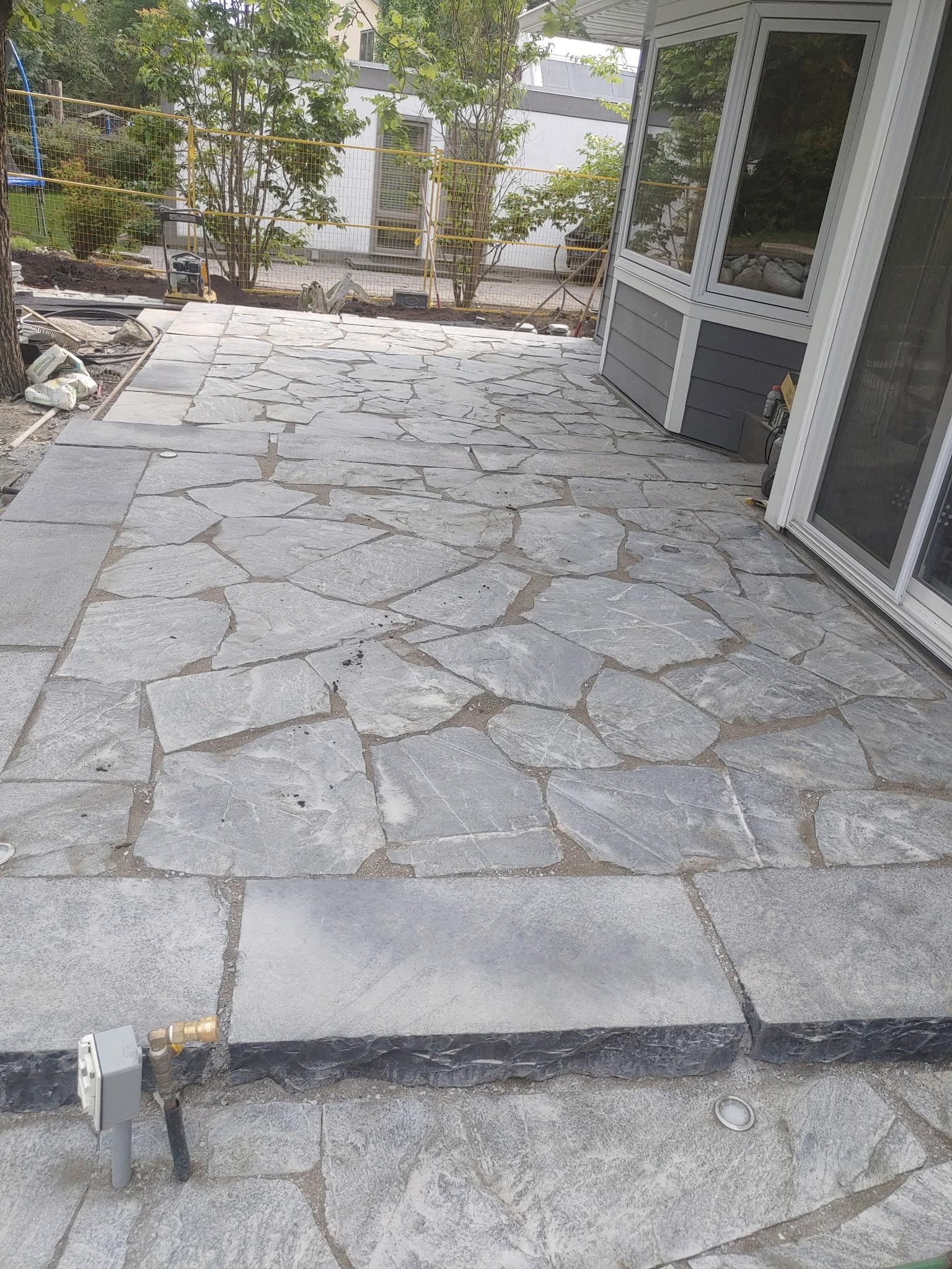 Large irregular flagstone patio installed beside house